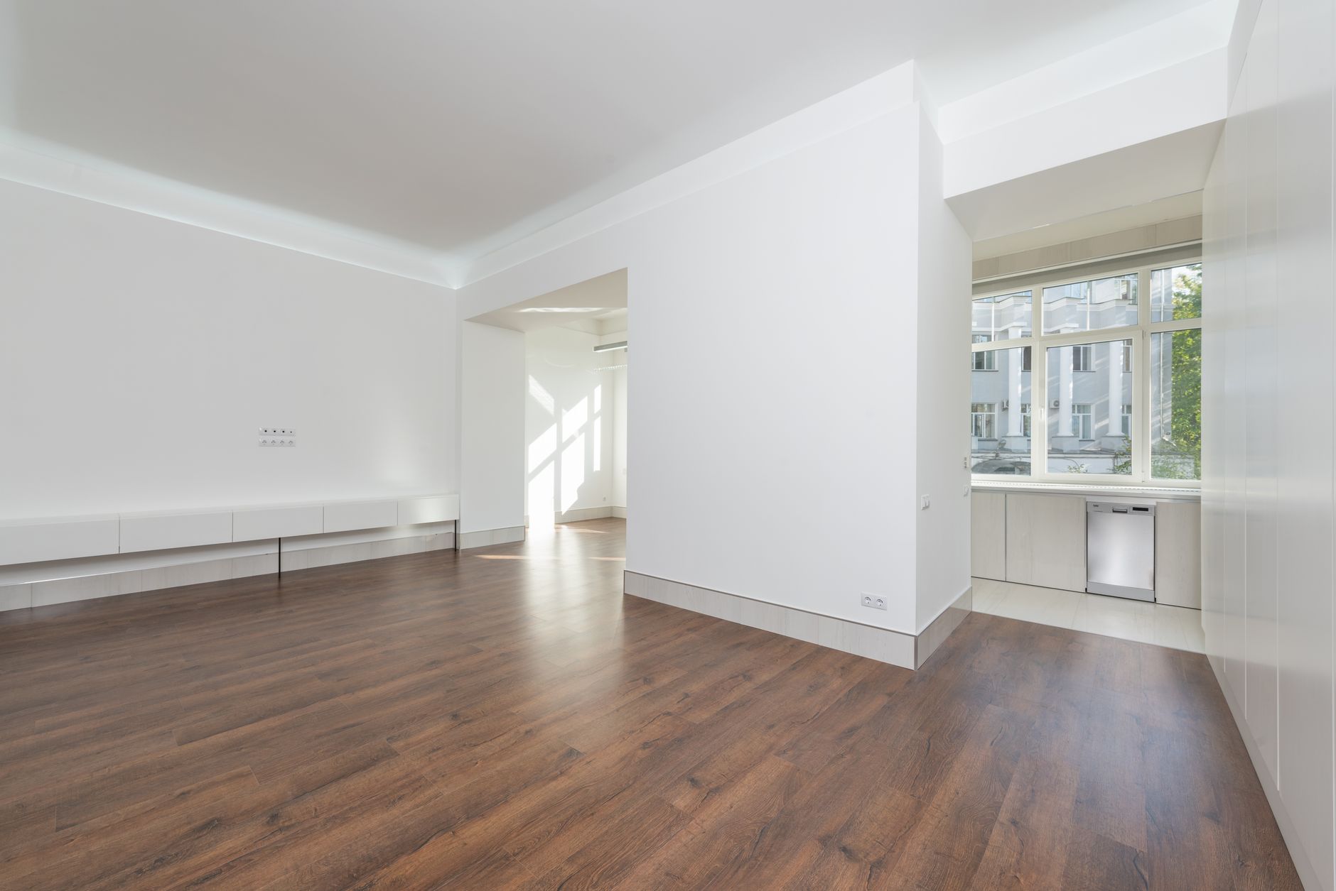A contemporary empty apartment with white walls and wooden flooring, featuring large windows