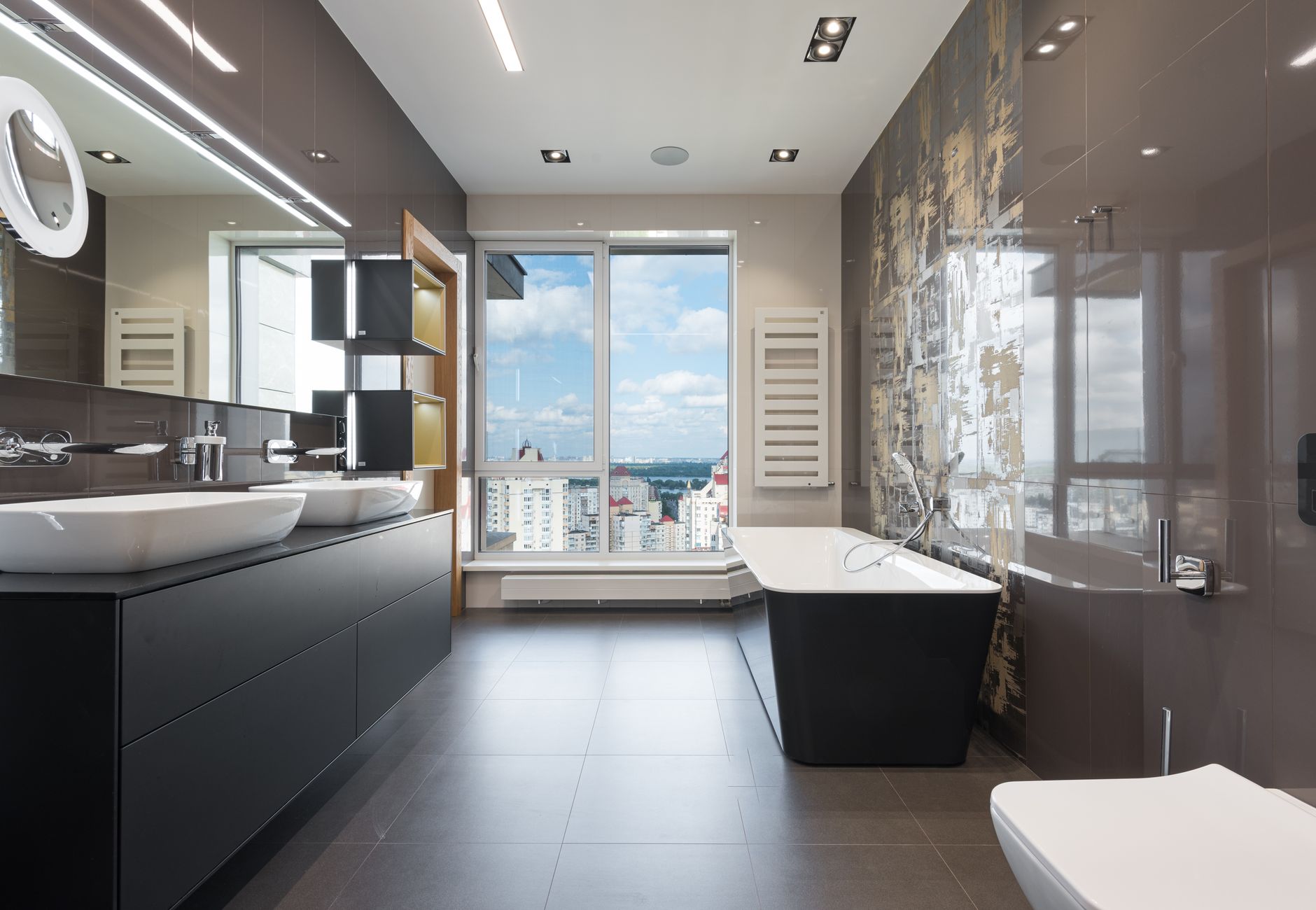 Large-format grey tile flooring in a contemporary Arkansas bathroom with a bathtub and twin ceramic sinks