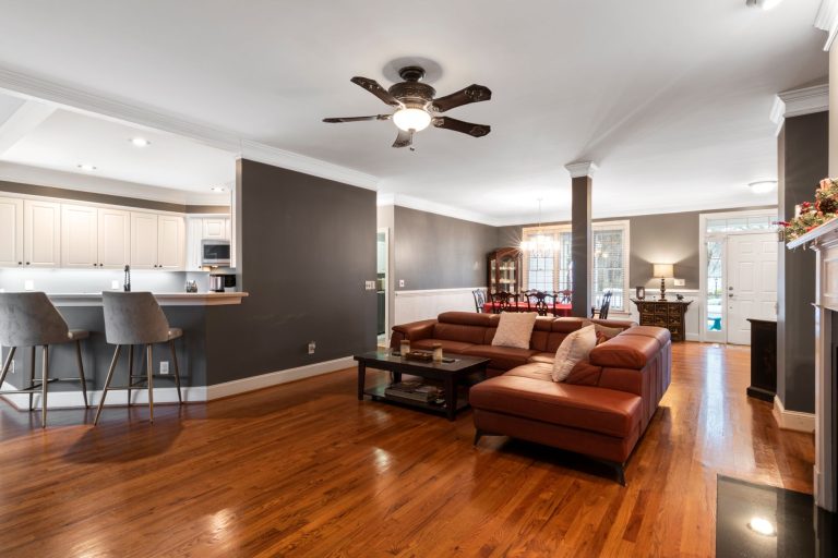 Hardwood flooring in an open Arkansas living room, with the kitchen island and large windows beyond